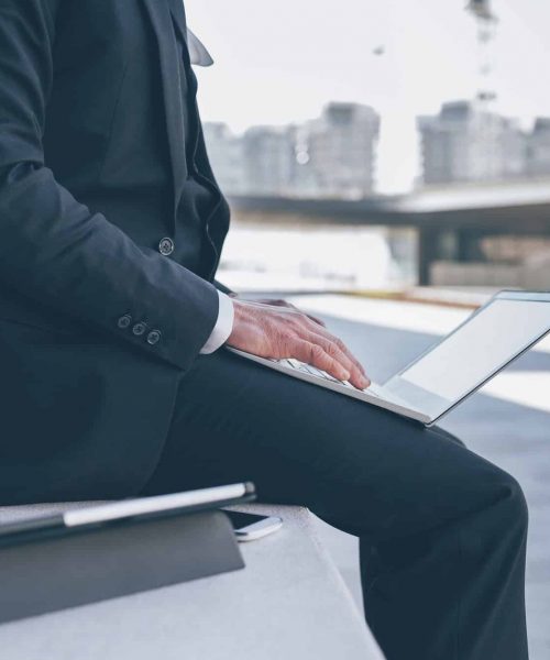 Unrecognizable professional businessman outdoor using computer Unrecognizable professional businessman outdoor using computer
